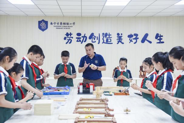 南宁市鲁班路小学，在老师指导下学生制作鲁班锁，传承鲁班木工制作文化